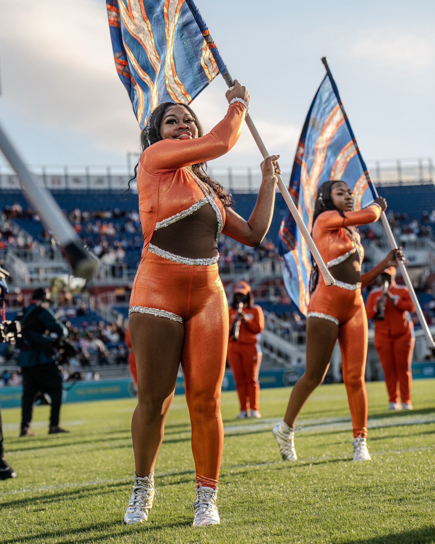 FMU flag corps performing on the field in orange and blue